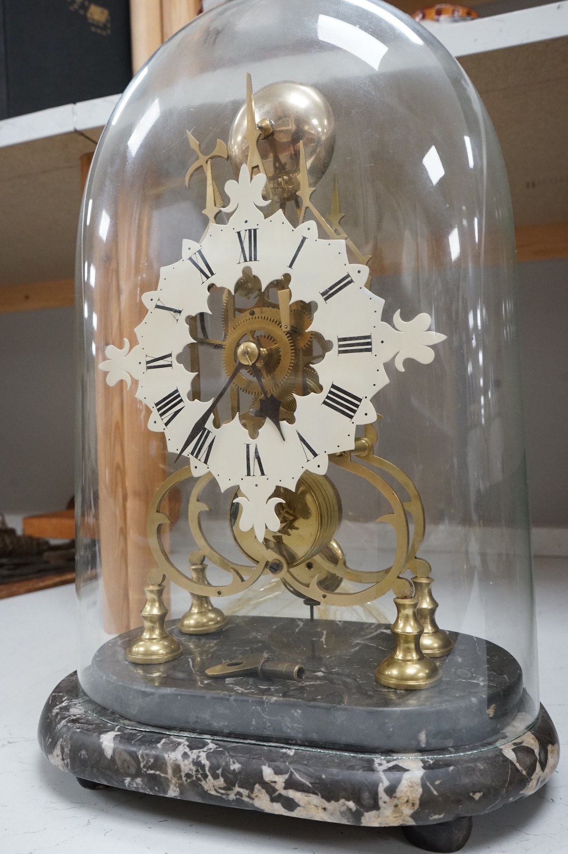 A large skeleton clock under dome, on grey marble base. 44cm high